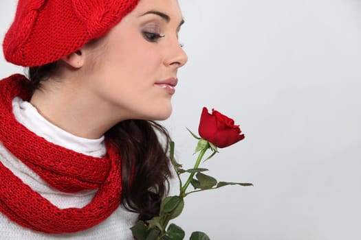 Woman in knitted hat smelling rose