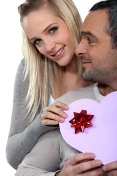 a woman giving a heart shaped box to her husband