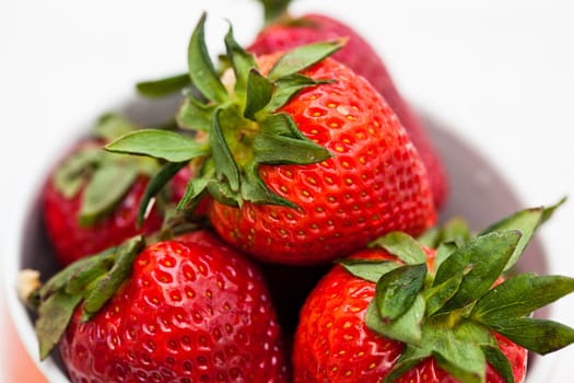 Closeup of large fresh strawberries in bowl against light background