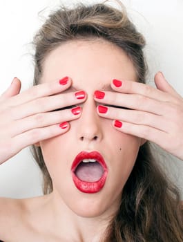 a charming young woman hiding her face behind her hands
