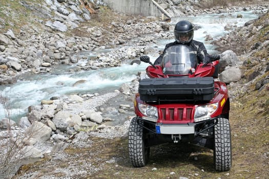 With the quad by the stream in the mountains