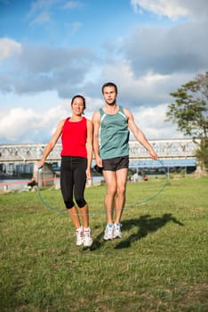 Young fitness couple exercising outdoor - jumping with skipping rope