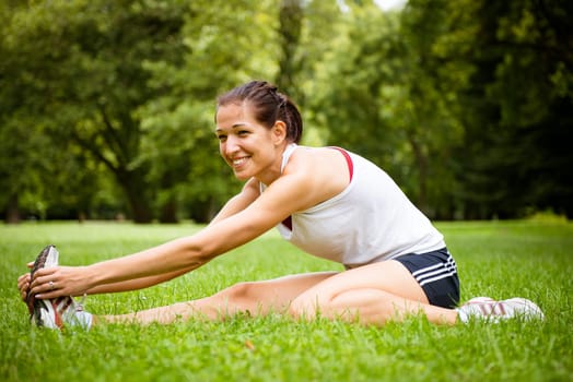 Young fitness woman stretching muscles before sport activity - outdoor in park