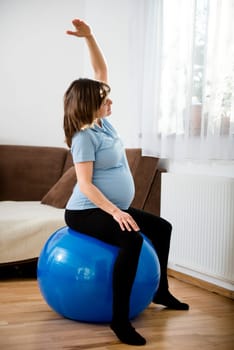 Pregnant woman exercising with fit ball at home