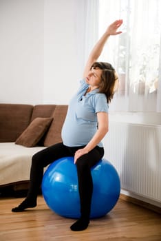 Pregnant woman exercising with fit ball at home