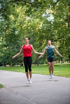 Young fitness couple exercising outdoor - jumping with skipping rope