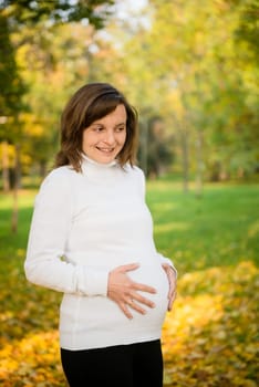 Young happy smiling pregnant woman outdoor in autumn nature