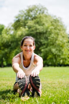 Young fitness woman stretching muscles before sport activity - outdoor in park