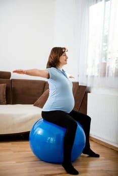 Pregnant woman exercising with fit ball at home