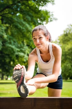 Young fitness woman stretching muscles before sport activity - outdoor in park