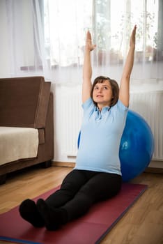 Pregnant woman exercising with fit ball at home