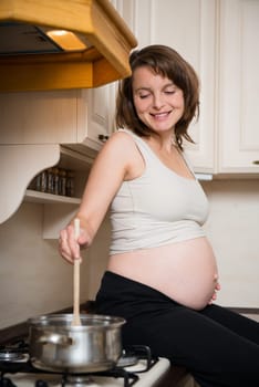 Lifestyle portrait of smiling pregnant woman cooking in home kitchen
