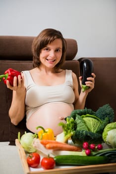 Lifestyle portrait of pregnant woman with vegetables in home kitchen
