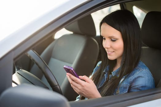 Young beautiful woman using smartphone while driving car