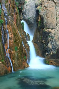 water falling to river between huge rocks