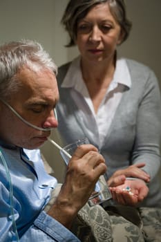 Caring senior wife holding drugs for her sick husband