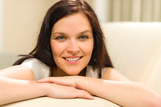 Smiling cheerful woman lying on couch looking at camera