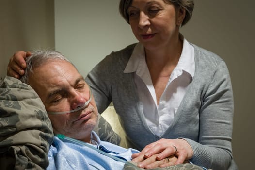 Caring female nurse with sleeping senior male patient