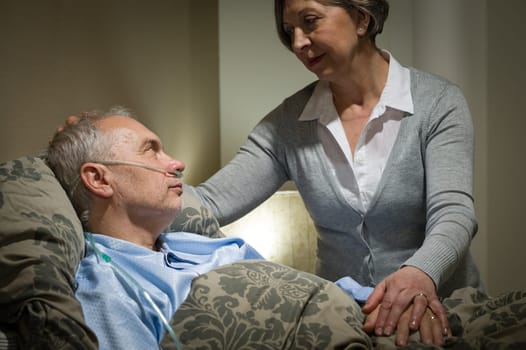 Worried senior woman caring with sick husband in the bedroom