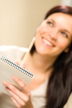 Smiling thinking woman holding notepad looking for inspiration