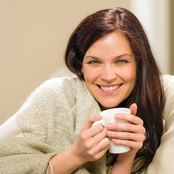 Portrait of joyful woman drinking hot beverage at home
