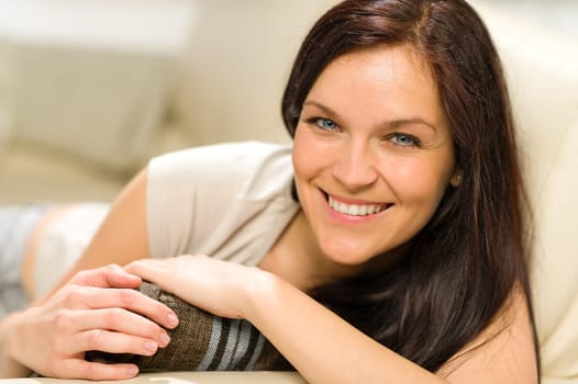 Serene cheerful woman lying on couch looking at camera