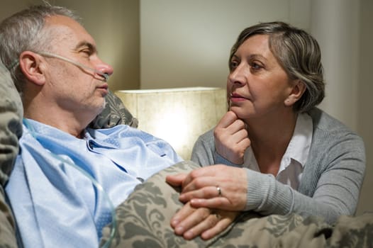 Senior patient at hospital with worried wife holding hands