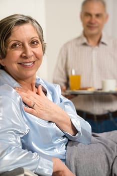 Retired husband bringing breakfast to bed to her ill wife