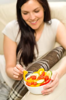 Joyful healthy woman eating bowl of fresh vegetables