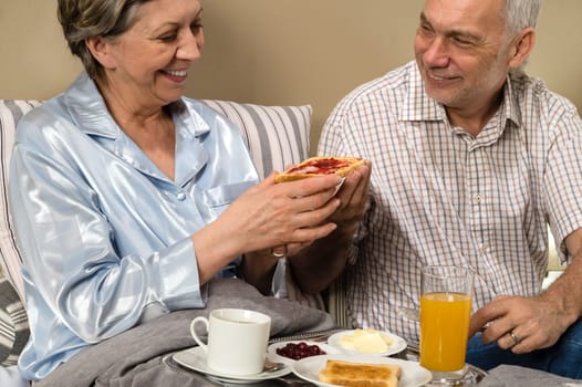 Senior couple having romantic morning breakfast in bed