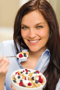 Portrait of happy woman eating cereal with yogurt and fruits