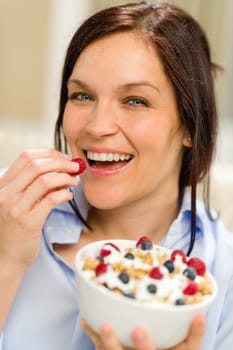 Joyful woman eating healthy cereal in the morning for breakfast