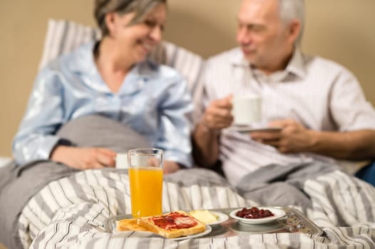 Pensioners drinking coffee and eating breakfast in the bed
