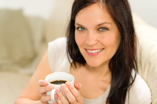 Smiling satisfied woman holding cup of espresso in cozy environment