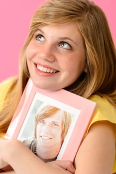 Joyful teenage girl embracing picture of her boyfriend