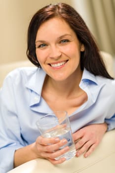 Joyful young woman holding glass of fresh water