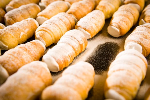 Puff pastries filled with whipped cream in powder sugar coating