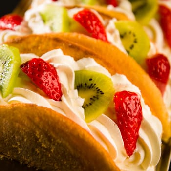 Sponge cake filled with strawberry and kiwi on whipped cream