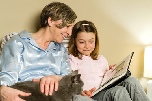 Grandmother and girl looking at photo album petting a cat