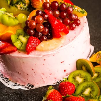 Fruit cake with cream coating and fresh fruits topping