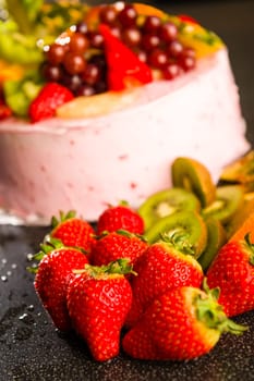 Fresh strawberries and kiwis with fruit cake background