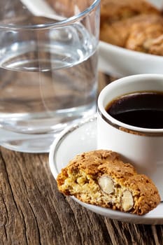 Fine cantuccini pastries,an espresso and a glass of water on a wooden surface