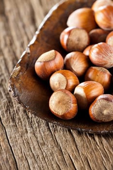 Whole hazelnuts in a very old wooden shovel on rustic wood background