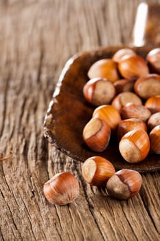 Whole hazelnuts in a very old wooden shovel on rustic wood background