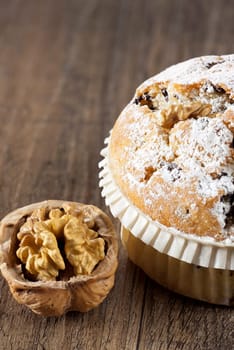 Large walnut chocolate muffin with a walnut on rustic wood background