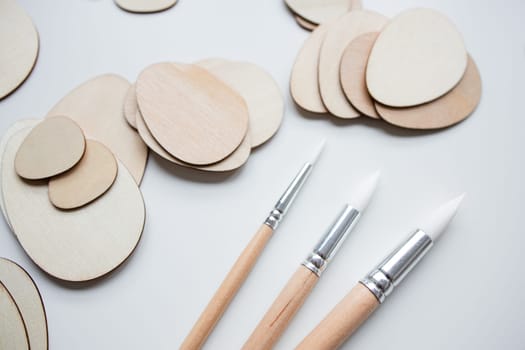 Wooden Easter egg shapes and brushes for crafting and art projects.