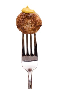 Fried meatball with yellow mustard on a fork in portrait format