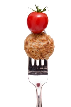 Fried meatball and red tomato on a fork