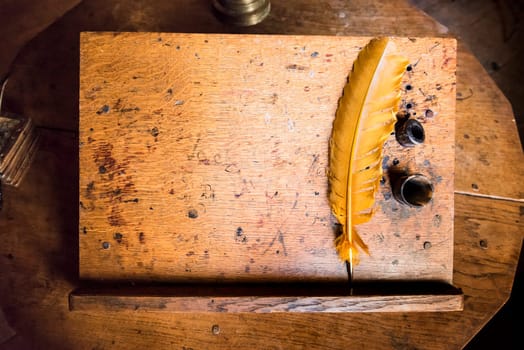 High angle shot of old quill and ink well on wooden writing desk