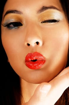 A closeup portrait of a gorgeous chinese woman blowing a kiss with her red lips for white background.